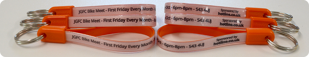 Three orange printed key fobs with silver metal rings and event details.